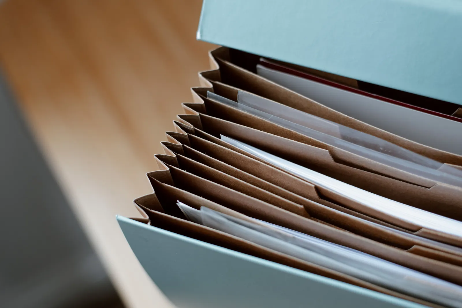 An accordion file of brown folders and papers opens on a wooden desk