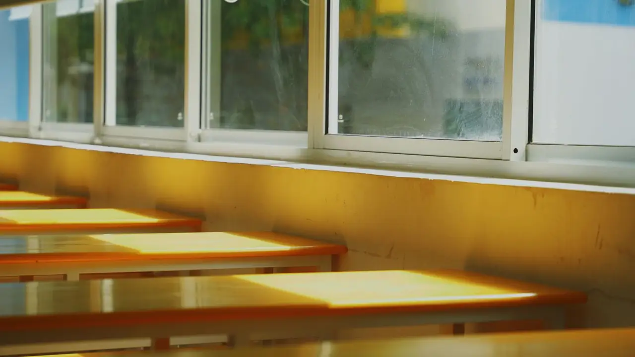 Late-afternoon sunlight falling gold across empty classroom desks along a window wall.