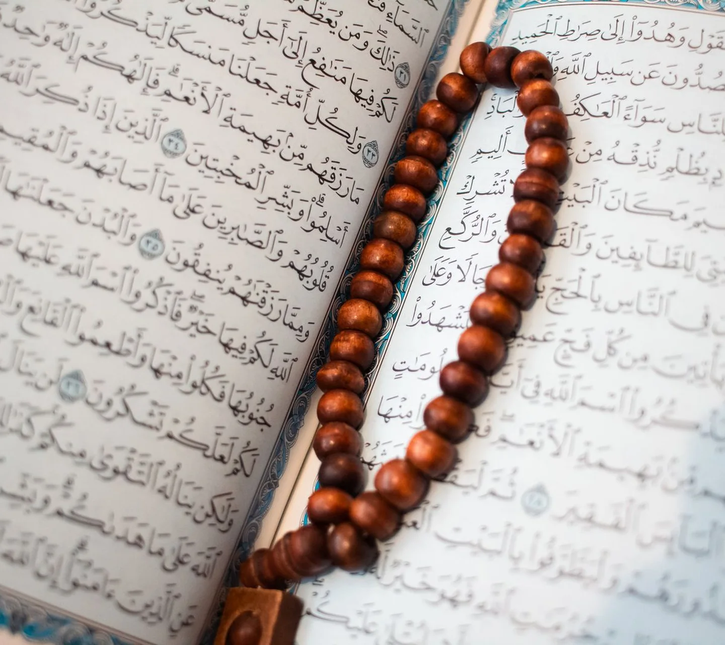 An open Qur'an with wooden prayer beads